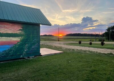 Golden sunset over open countryside beside the colourful rental cabin with green metal roof at French Creek RV in Fawcett, Alberta.